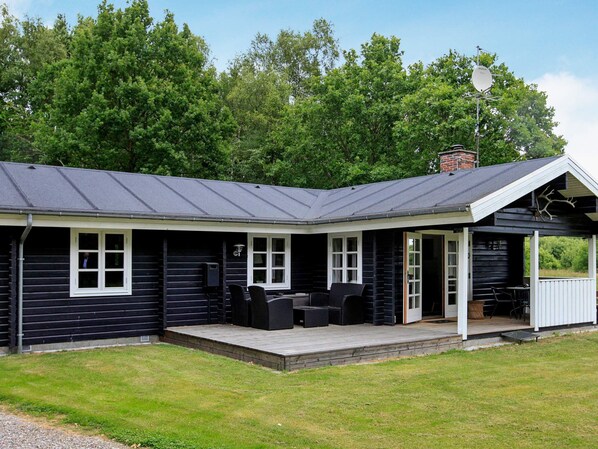 A cabin with a covered porch, a chimney, and a satellite dish.