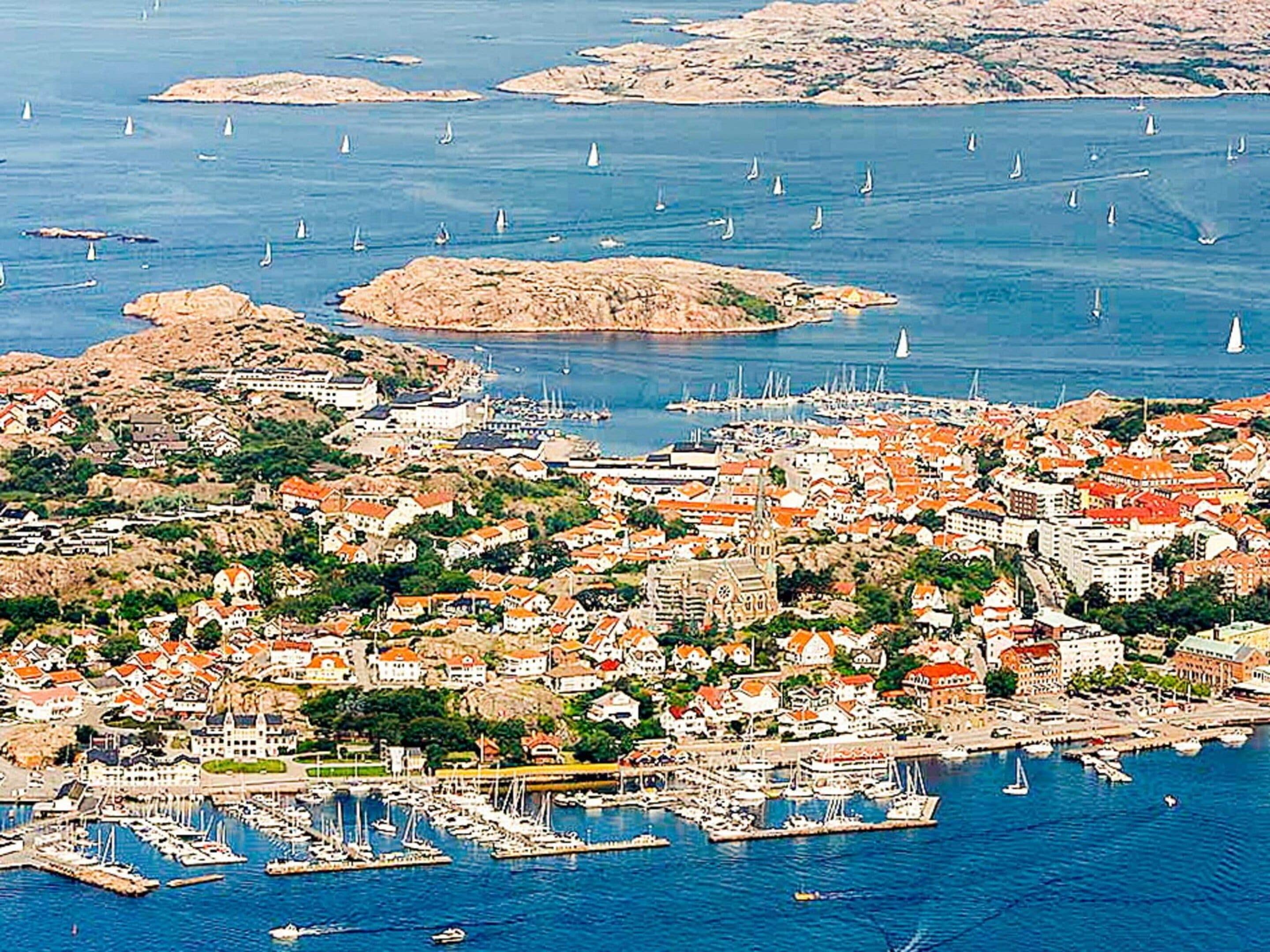 A coastal town with a marina, boats, and buildings with red roofs.