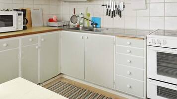 Une cuisine avec des meubles blancs, un four à micro-ondes, une cuisinière et un évier.