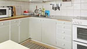 A kitchen with white cabinets, a microwave, a stove, and a sink. - 3 Person Holiday Home in Lysekil (Lysekil)