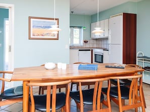 A dining area with a wooden table, black chairs, a white teapot, and a framed picture on the wall. - 4 Star Holiday Home in Blavand (Blavand)