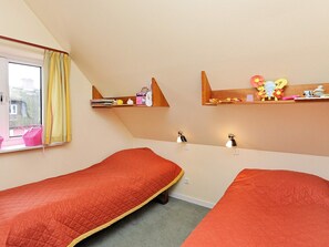 Une chambre de dortoir avec deux lits simples, une fenêtre avec des rideaux jaunes et des étagères remplies de divers objets.