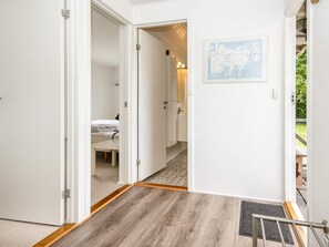 A hotel room with a wooden floor, a bed with white bedding, a bathroom with a sink and mirror, and a map on the wall. - 6 Person Holiday Home in Kolind-by Traum (Kolind)