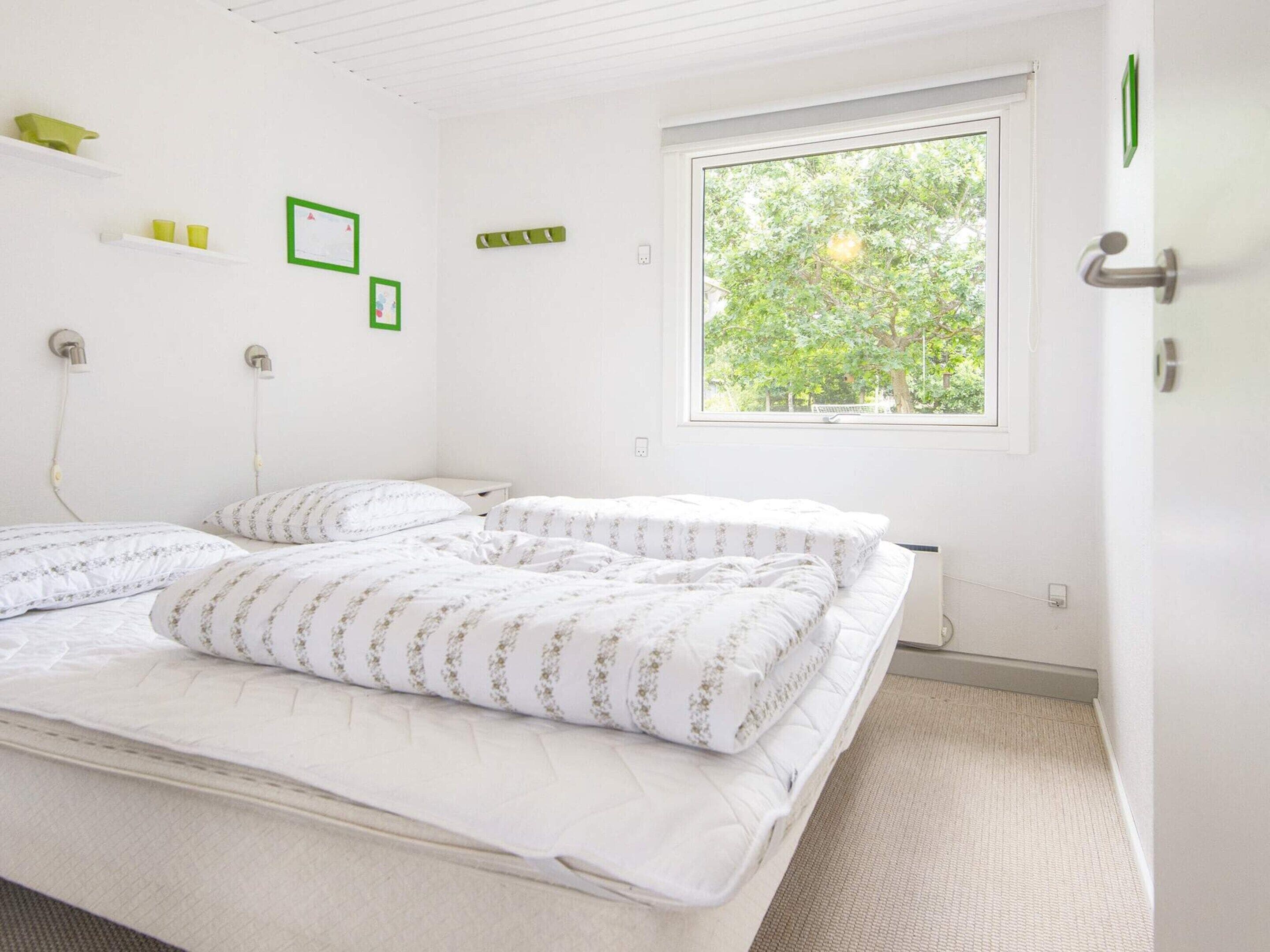 A bedroom with a bed, a window, and a door.