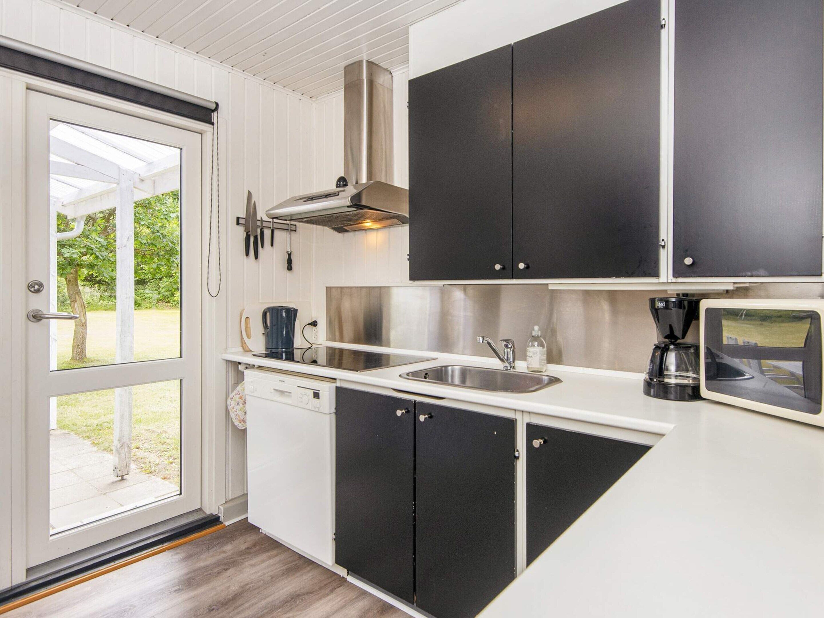 A compact kitchen with a sink, stove, and coffee maker.