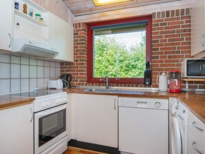 Cozinha compacta com janela, micro-ondas, torradeira e cafeteira.