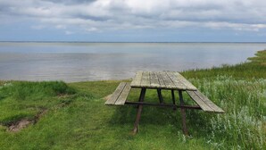 A wooden picnic table on a grassy area by a calm body of water. - 6 Person Holiday Home in Orsted-by Traum (Ørsted)