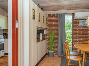 A modern kitchen with a microwave, toaster, and oven. There is a dining area with a table and chairs, and a potted plant.