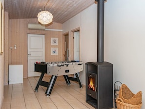 A cozy room with a wooden ceiling, a foosball table, a fireplace, and a wall-mounted air conditioning unit.