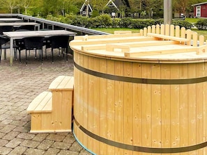A wooden hot tub with benches, a covered seating area, and a brick patio. - 4 Star Holiday Home in Glesborg (Glesborg)