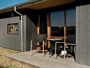 A wooden deck with outdoor seating, a window, and a metal gutter. - 8 Person Holiday Home in Ulfborg (Ulfborg)