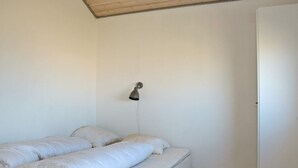 A single bed with a headboard, a bedside lamp, and a wooden floor.