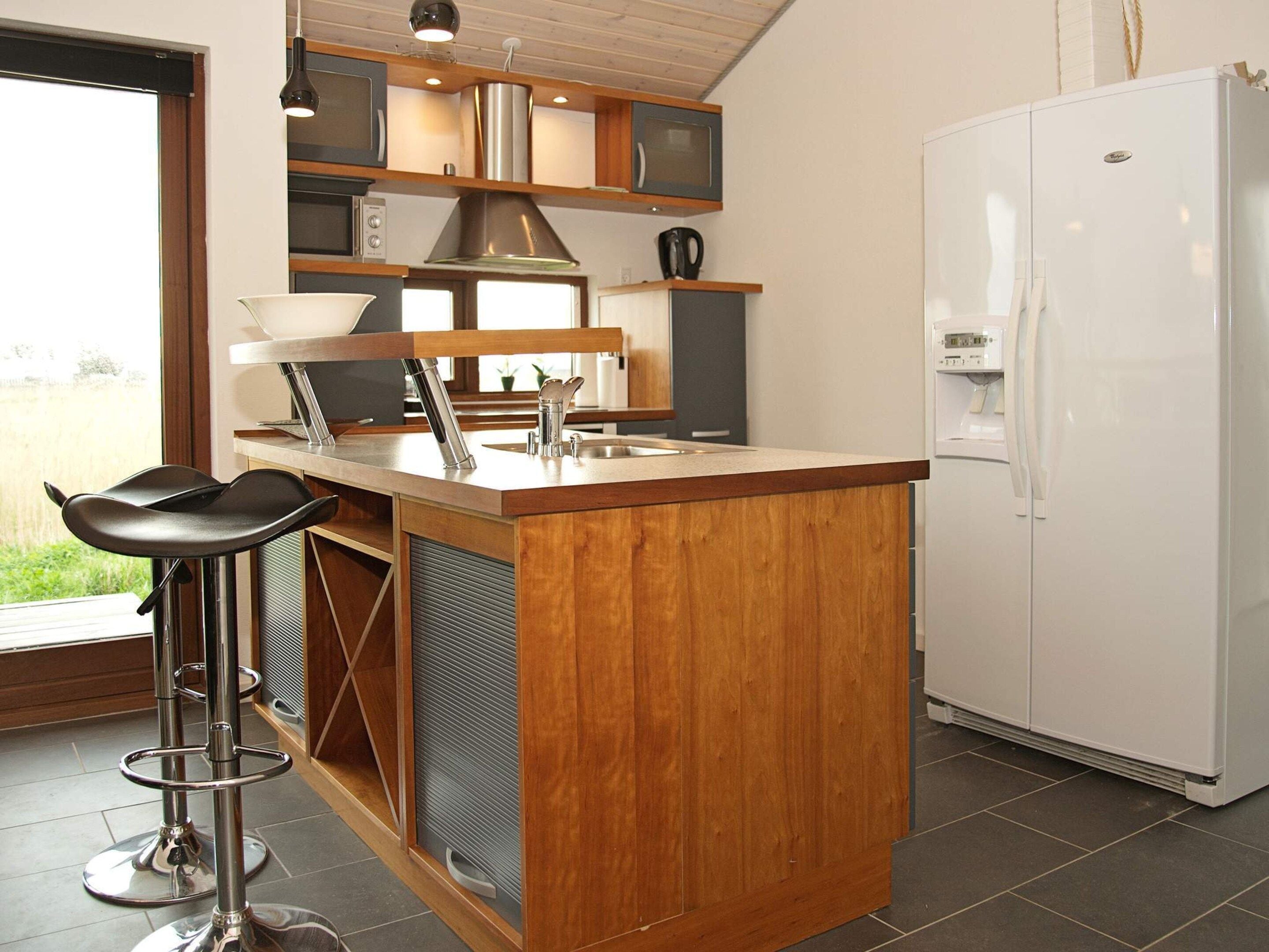 Cozinha com ilha de madeira, eletrodomésticos de aço inoxidável e geladeira branca.