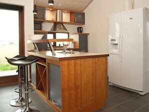 A kitchen with a wooden island, stainless steel appliances, and a white refrigerator. - 8 Person Holiday Home in Ulfborg (Ulfborg)