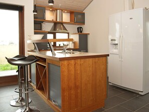 A kitchen with a wooden island, stainless steel appliances, and a white refrigerator.