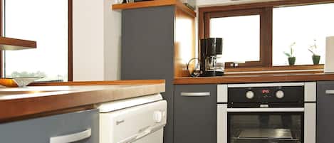 Cocina compacta con lavavajillas, microondas, cafetera y horno.