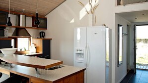 A modern kitchen with a white refrigerator, wooden cabinets, and a large island with a sink.