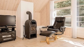A cozy room with a wooden interior, a fireplace, a leather chair, and a television on a cart.