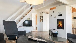A modern living room with a fireplace, a television, and a staircase.