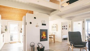 A modern living room with a fireplace, wooden flooring, and a high ceiling with exposed beams.