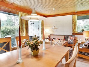 A wooden dining table with chairs, a vase of flowers, and pendant lighting. - Rustic Holiday Home in Asnæs near Sea (Asnaes)