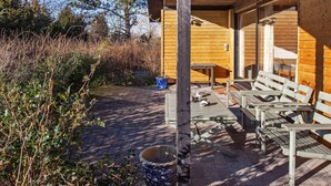 A wooden cabin with a covered patio area, outdoor seating, and a stone pathway. - Rustic Holiday Home in Asnæs near Sea (Asnaes)