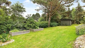 A well-maintained garden with a wooden shed, a large tree, and various shrubs. - Rustic Holiday Home in Asnæs near Sea (Asnaes)