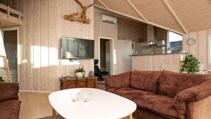 Een gezellige woonkamer met een bruine bank, een witte salontafel en een wandtelevisie.