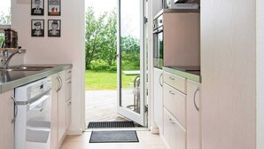 A modern kitchen with a large window, stainless steel appliances, and a clock on the wall. - 8 Person Holiday Home in Brovst (Brovst)