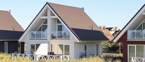 A row of modern houses with a flat roof, a balcony, and a white fence.