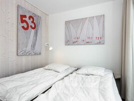 A hotel room with two single beds, a large number 53 painting, and a sailboat painting on the wall.
