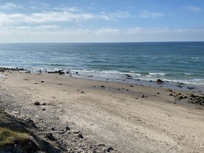 A beach with a rocky shoreline and calm sea. - 6 Person Holiday Home in Hirtshals (Hirtshals)
