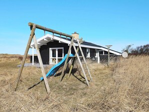 A house with a blue slide in a grassy field.