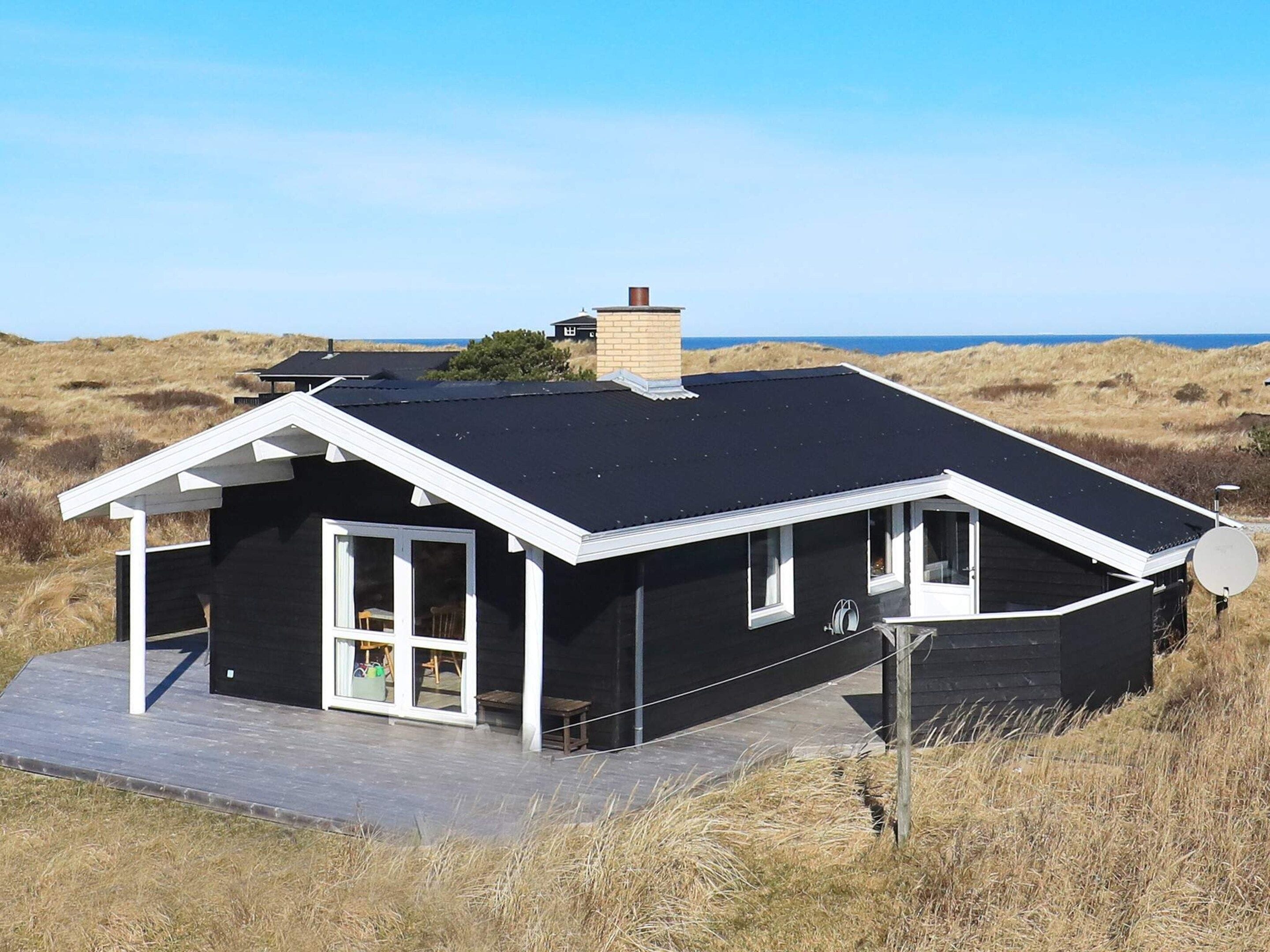 A modern black house with a flat roof, white trim, and a satellite dish.