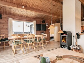 A cozy cabin interior with a dining area, a fireplace, and a kitchen. - 6 Person Holiday Home in Hirtshals (Hirtshals)