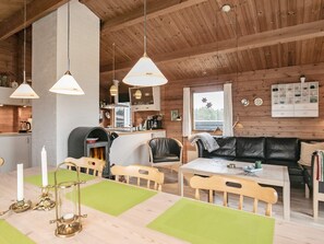 A cozy cabin interior with a dining area, a fireplace, wooden furniture, and pendant lighting. - 6 Person Holiday Home in Hirtshals (Hirtshals)