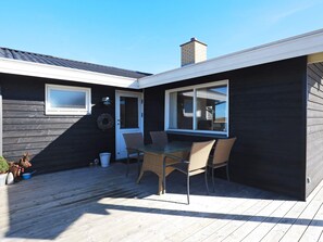A deck with a table and chairs, a door, and a window. - 6 Person Holiday Home in Hirtshals (Hirtshals)
