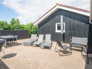 An outdoor patio with a grill, lounge chairs, and a wooden wall. - 6 Person Holiday Home in Hemmet (Hemmet)