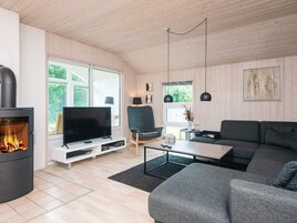 Una sala moderna con chimenea, televisor, sofá y sillón.