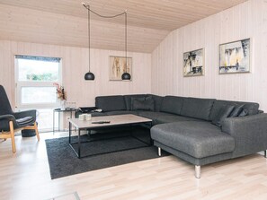 A modern living room with a grey sectional sofa, a small coffee table, a black rug, and two pendant lights.