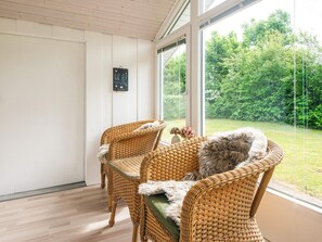 A room with wicker furniture, a view of greenery outside, and a wall-mounted sign. - 6 Person Holiday Home in Hemmet (Hemmet)