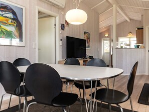 A dining area with a round table, black chairs, a flat-screen TV, and a pendant light. - 5 Star Holiday Home in Hadsund (Hadsund)