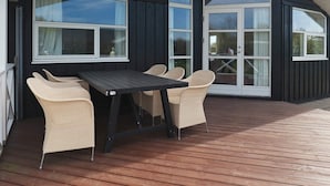 A covered outdoor area with a table and chairs, large windows, and a door. - 5 Star Holiday Home in Hadsund (Hadsund)