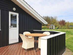 A deck with a table and chairs, a door, and a small garden area with a gazebo. - 5 Star Holiday Home in Hadsund (Hadsund)
