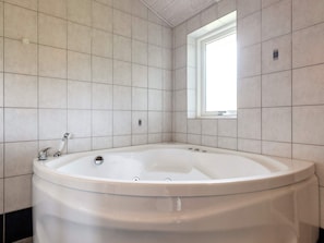 A bathroom with a freestanding bathtub, a window, and tiled walls. - 5 Star Holiday Home in Hadsund (Hadsund)