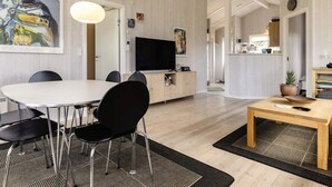 A modern living room with a dining area, a TV, and a kitchen in the background. - 5 Star Holiday Home in Hadsund (Hadsund)