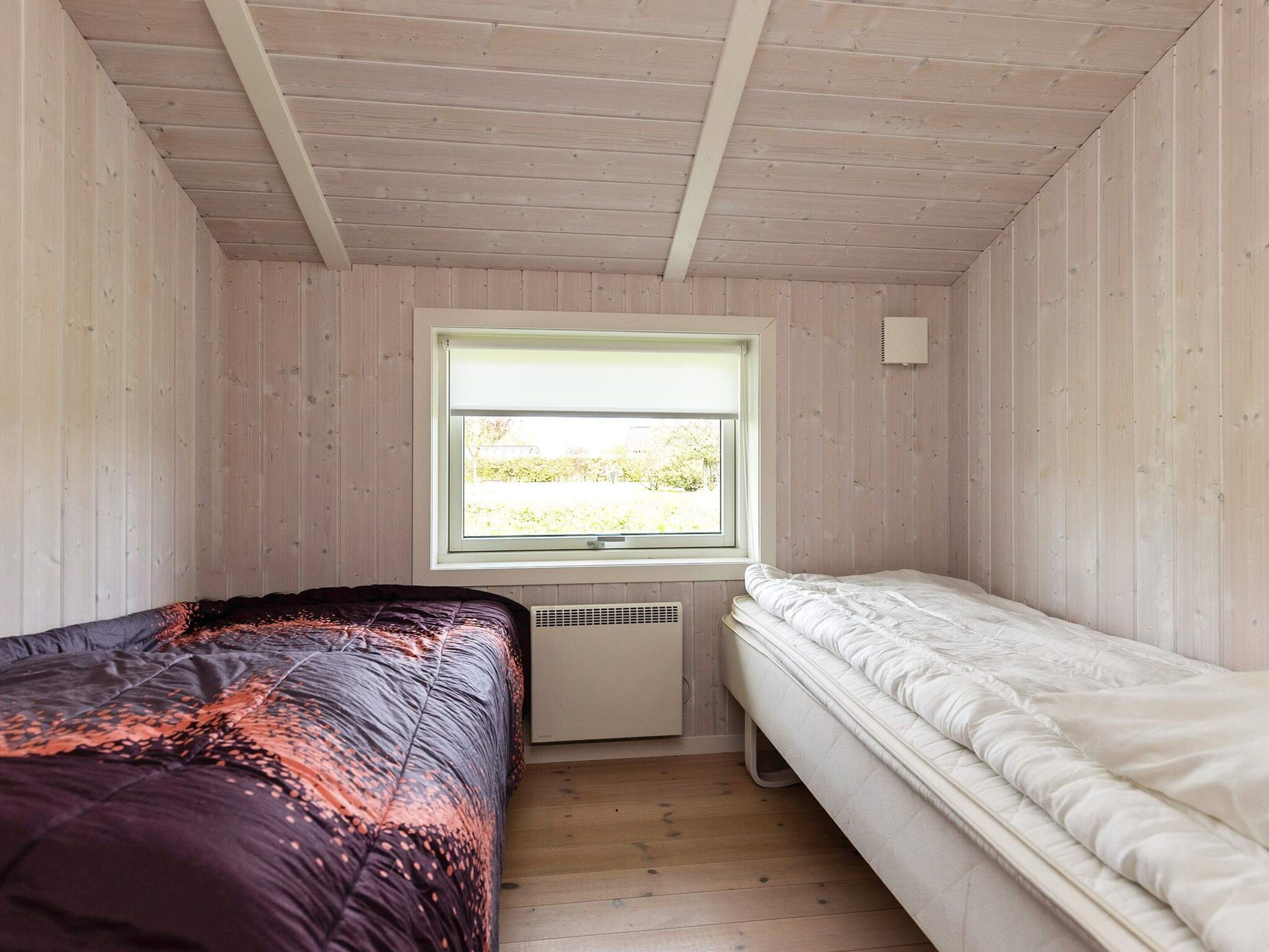 A small room with two beds, a window, and a radiator.
