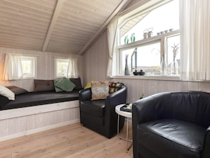 A cozy room with a built-in bench, a black leather chair, and a small table. - 5 Star Holiday Home in Hadsund (Hadsund)