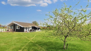 A house with a covered porch, a lawn, and a tree. - 5 Star Holiday Home in Hadsund (Hadsund)