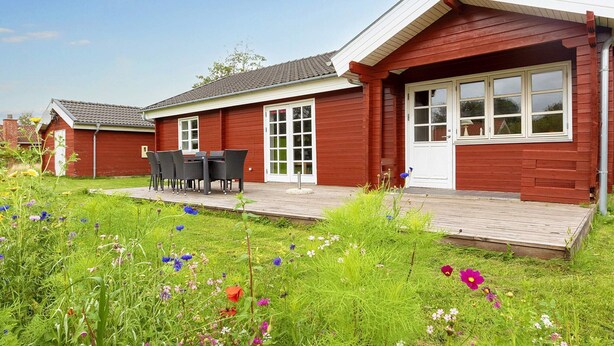 A red wooden house with a porch, a table, and chairs. - 4 Star Holiday Home in Vinderup (Vinderup)